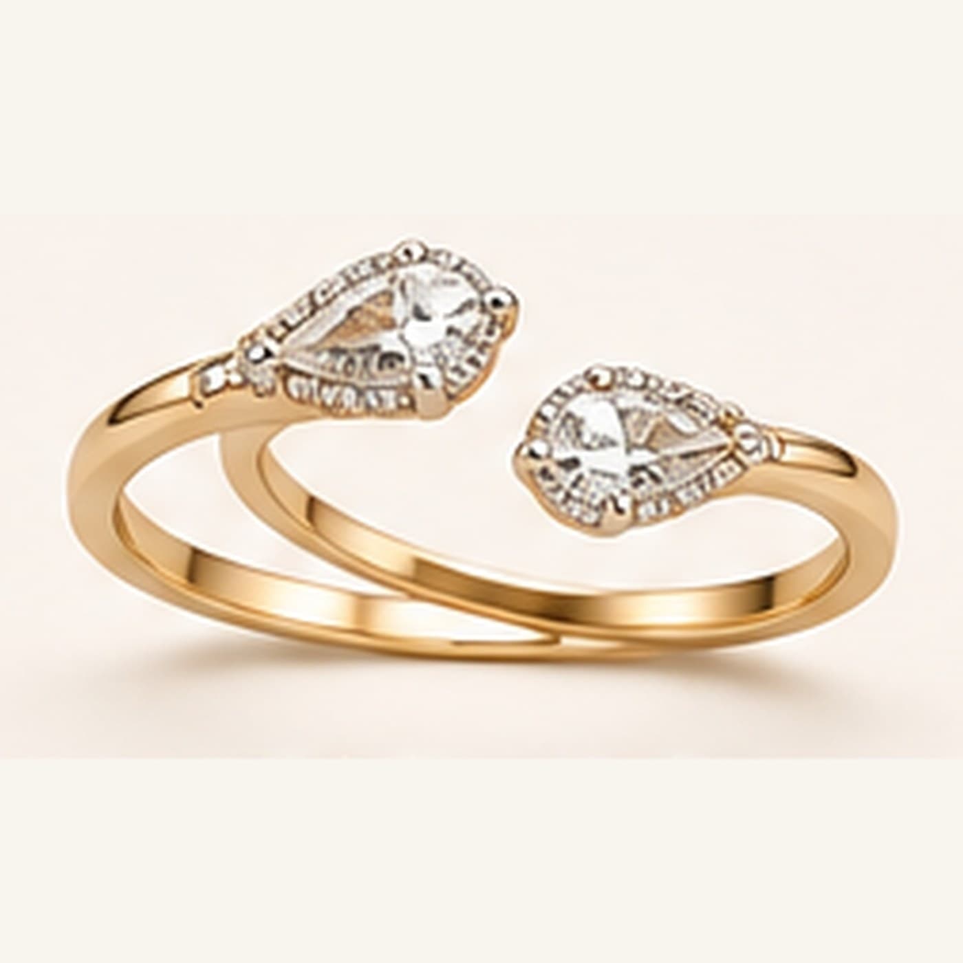 Gold bypass ring with two pear-shaped diamond clusters, photographed on cream