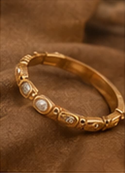 A heritage gold and diamond bangle resting on warm brown fabric