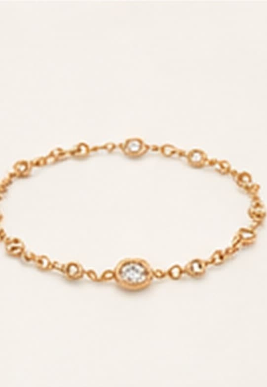 A delicate gold and diamond bracelet on a neutral ground