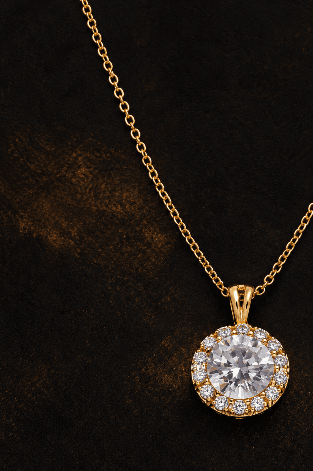 Round brilliant diamond pendant on a fine gold chain against a dark backdrop